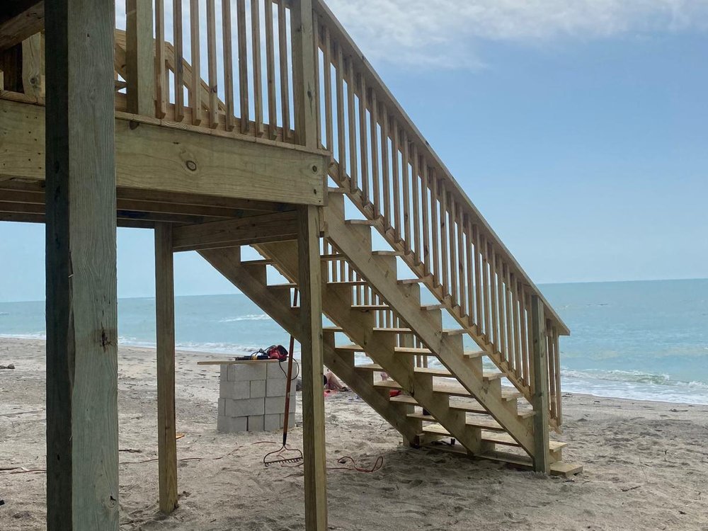 Newly built pressure-treated wood deck and staircase leading down to a beach