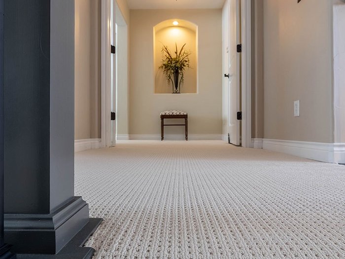 Tight angle of textured berber carpet hallway with a contrasting woven runner leading toward an arched doorway